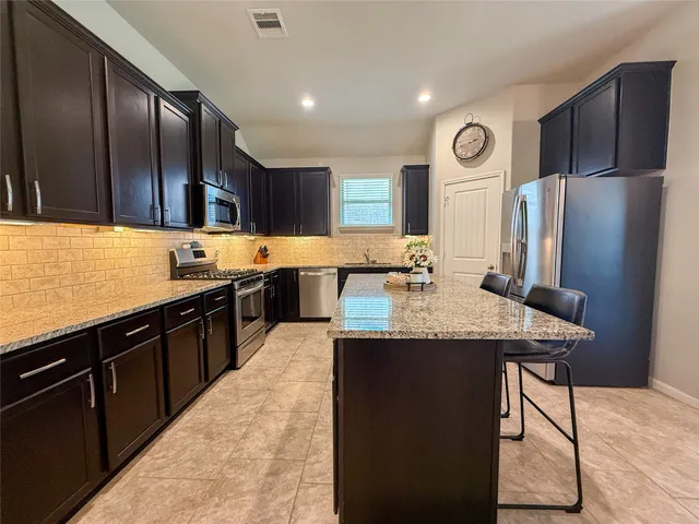 a kitchen with stainless steel appliances granite countertop a sink stove and refrigerator