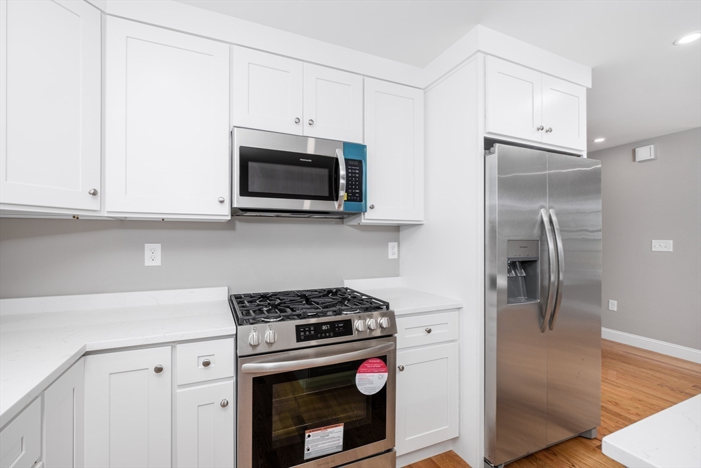 216 Vane Street, Unit 2 Revere, MA 02151 - Photo 4 of 22 a kitchen with cabinets stainless steel appliances and wooden floor
