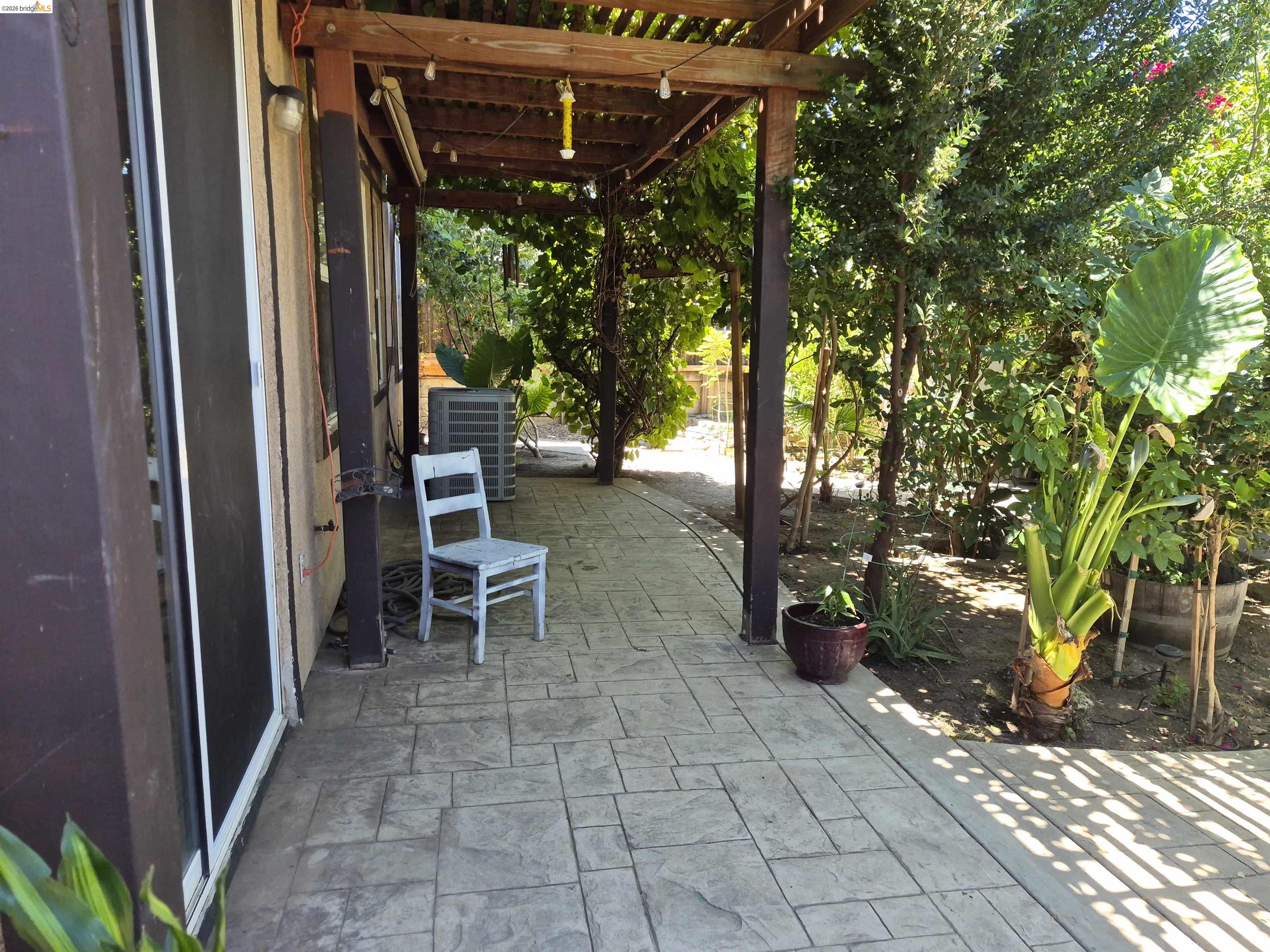 149 Oakpoint Court Bay Point, CA 94565 - Photo 17 of 22 Stained concrete patio with a wood pergola, bordered by mature trees and lush plantings