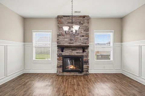 a view of an empty room with wooden floor fireplace and a window