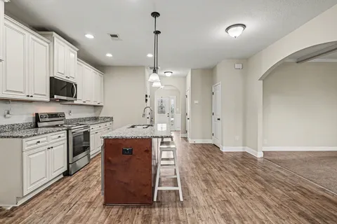 a large kitchen with stainless steel appliances granite countertop a stove and a wooden floors