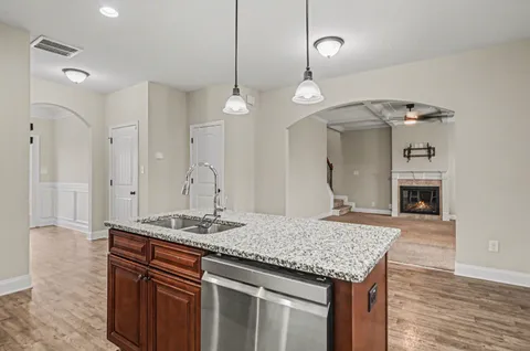 a kitchen with kitchen island granite countertop a sink cabinets and wooden floor