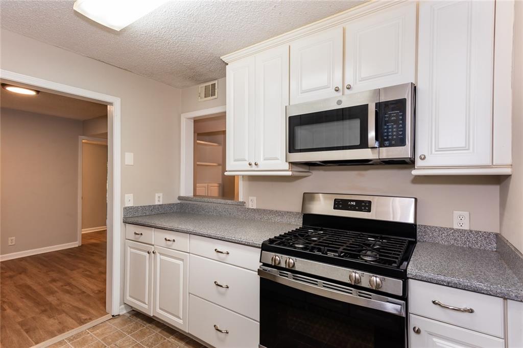 591 Emory Oaks Way, Unit 591 Decatur, GA 30033 - Photo 21 of 33 a kitchen with stainless steel appliances granite countertop white cabinets and a stove a oven with white countertops