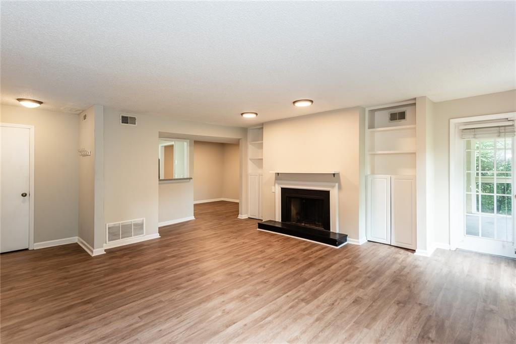 591 Emory Oaks Way, Unit 591 Decatur, GA 30033 - Photo 10 of 33 an empty room with wooden floor fireplace and windows