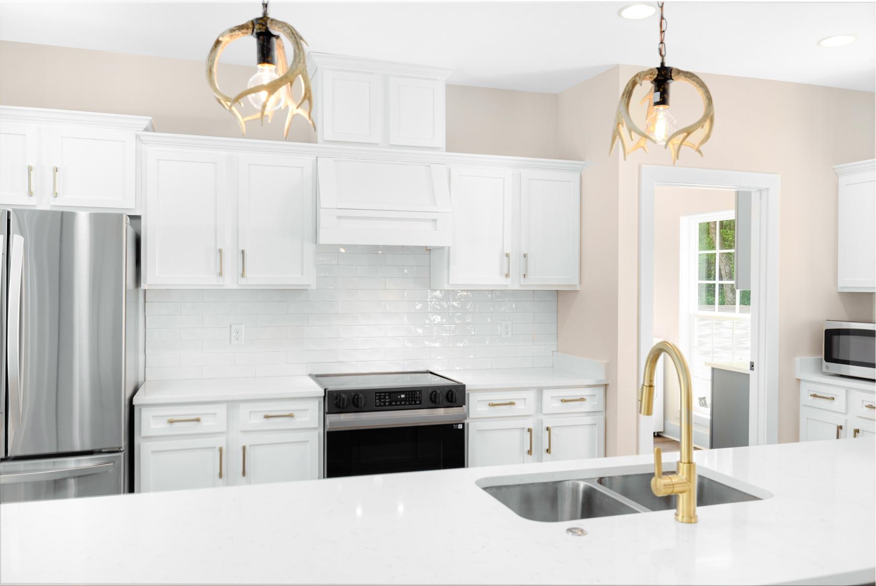 5702 Spring Lake Road Memphis, TN 38135 - Photo 14 of 40 Kitchen featuring white shaker cabinetry, white subway tile backsplash, stainless steel appliances, white countertops, and a gold-finish faucet