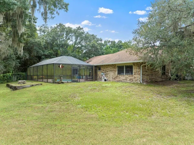 an aerial view of a house with swimming pool and large trees