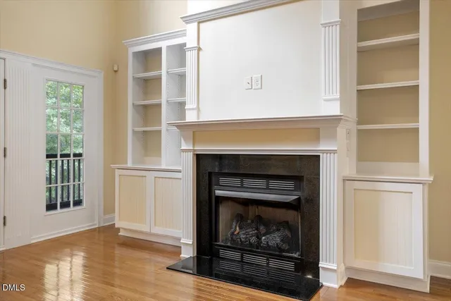a view of empty room with wooden floor and fireplace