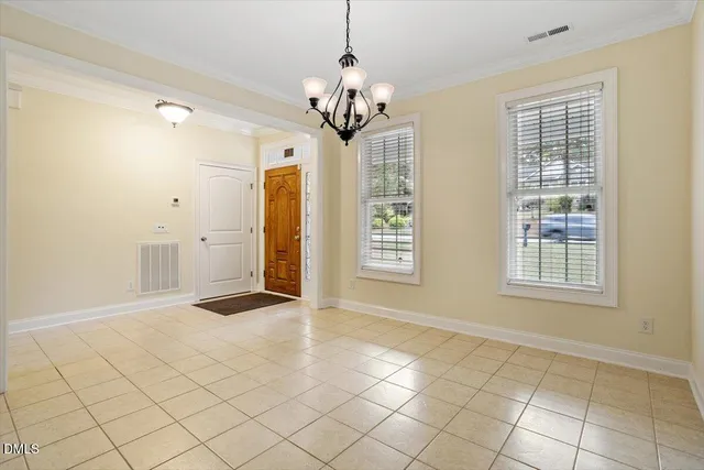an empty room with windows and chandelier fan