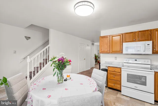 a dining hall with a stove a sink dishwasher and white appliances with wooden floor