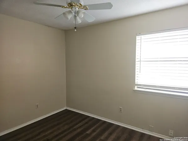 an empty room with a window and a fan
