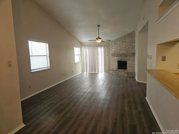 an empty room with wooden floor a ceiling fan and windows
