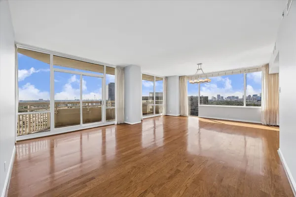 a view of an empty room with wooden floor and a large window