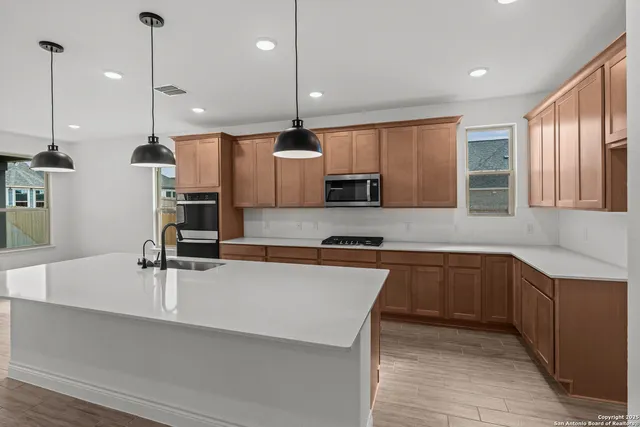 a kitchen with stainless steel appliances a sink a stove a refrigerator and cabinets