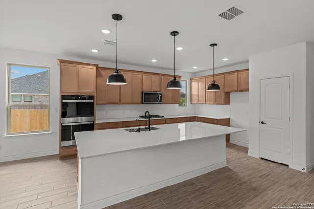 a large kitchen with kitchen island a large counter top stainless steel appliances and cabinets