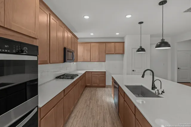 a kitchen with kitchen island granite countertop a sink a counter space appliances and cabinets