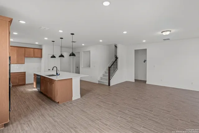 an open kitchen with kitchen island a sink appliances and a living room