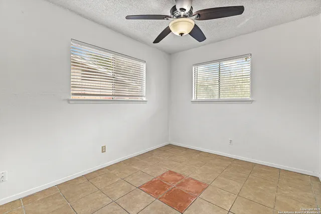an empty room with windows and fan