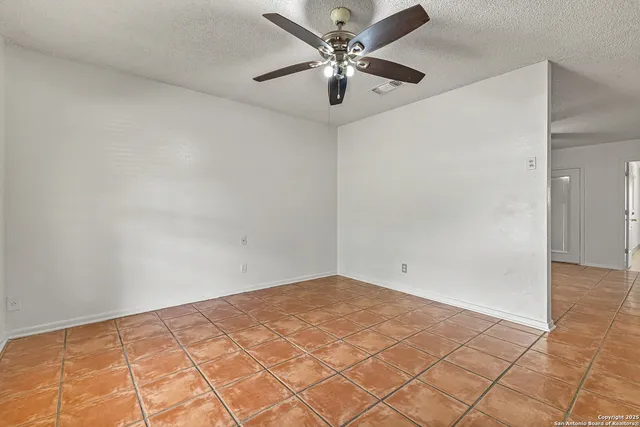 an empty room with a chandelier fan and windows