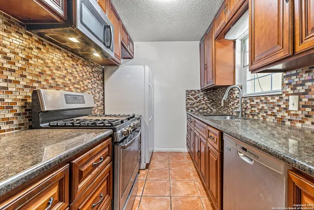 a kitchen with stainless steel appliances granite countertop a sink and a stove