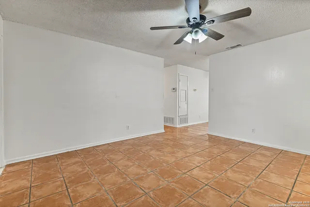 a view of an empty room and chandelier fan