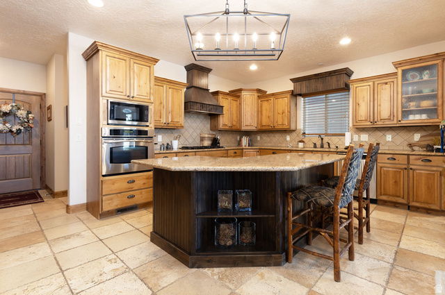 382 Ridgeview Street, Unit 8 & 9 Brian Head, UT 84719 - Photo 34 of 52 Spacious kitchen featuring an angled island with a granite countertop, light wood cabinetry, stainless steel double ovens, and tile flooring
