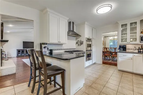 a kitchen with stainless steel appliances granite countertop a stove top oven a sink a dining table and chairs