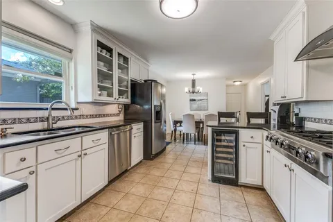 a kitchen with stainless steel appliances granite countertop a stove top oven a sink dishwasher a dining table and chairs with wooden floor