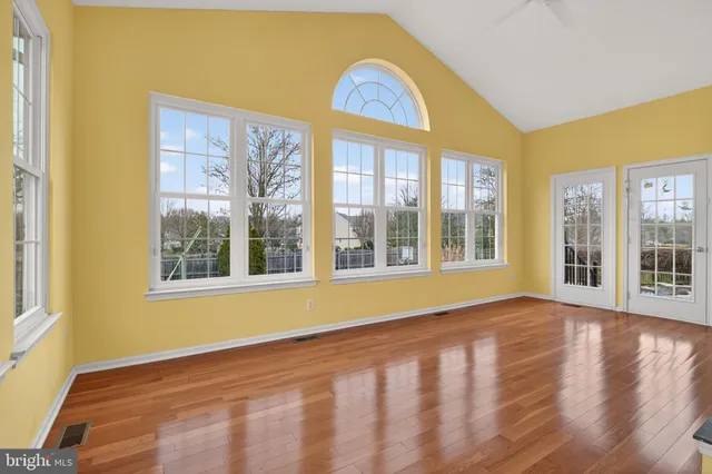 a view of an empty room with wooden floor fireplace and a window