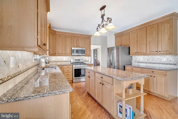 a kitchen with stainless steel appliances granite countertop a stove a kitchen island a table and chairs