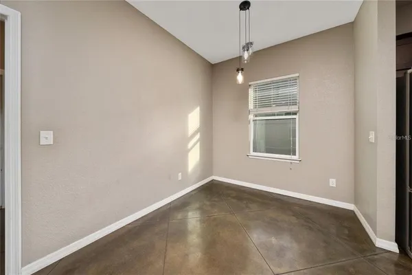 an empty room with a chandelier fan and windows