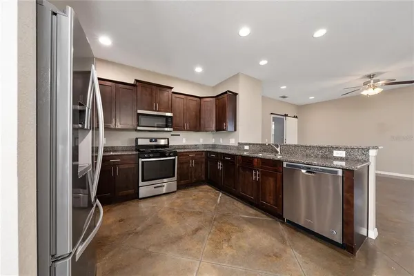 a kitchen with stainless steel appliances granite countertop a stove top oven a sink and a refrigerator