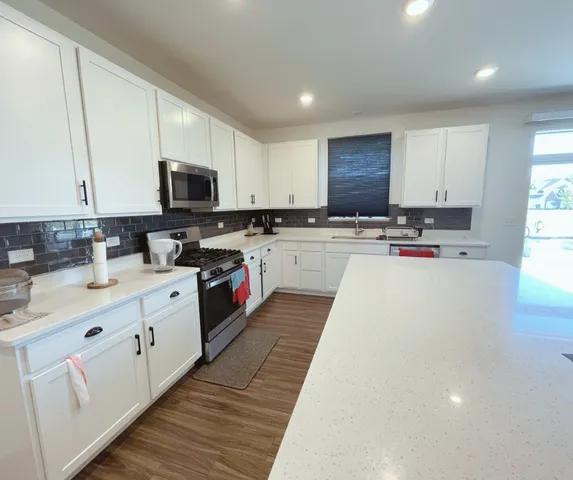 a kitchen with kitchen island granite countertop a sink a stove top oven a refrigerator a counter top space and cabinets