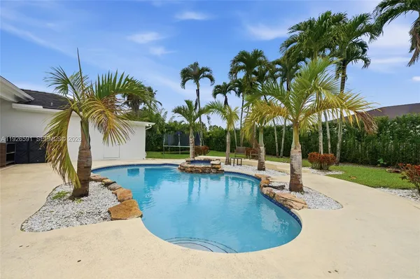 a view of a swimming pool with a lounge chair and palm trees