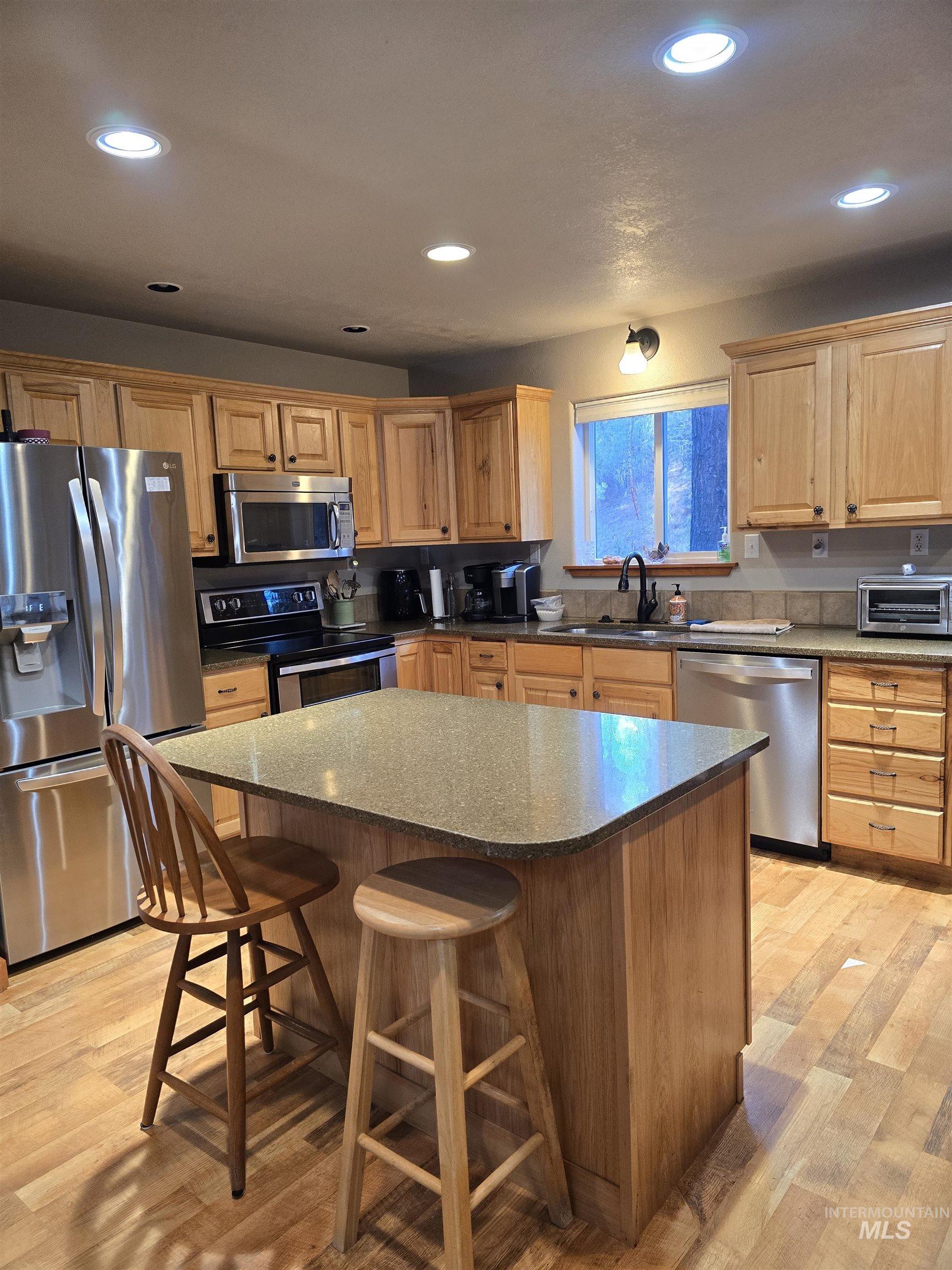 14 Forest Trail Road Garden Valley, ID 83622 - Photo 11 of 45 Kitchen with stainless steel appliances, a breakfast bar, a kitchen island, recessed lighting, and light wood-style floors