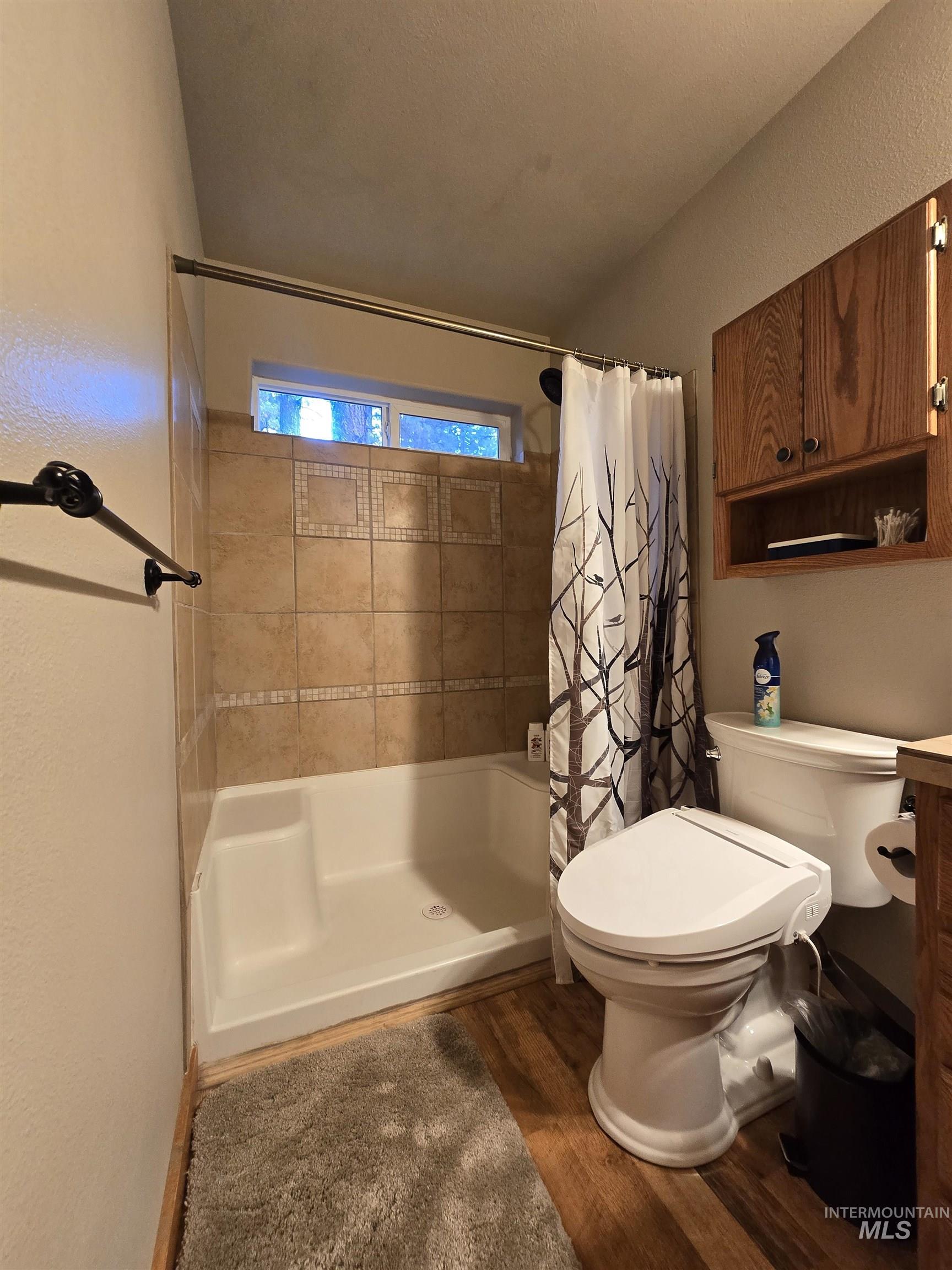 14 Forest Trail Road Garden Valley, ID 83622 - Photo 25 of 45 Bathroom featuring dark wood-style floors, vanity, a shower stall, and a textured wall