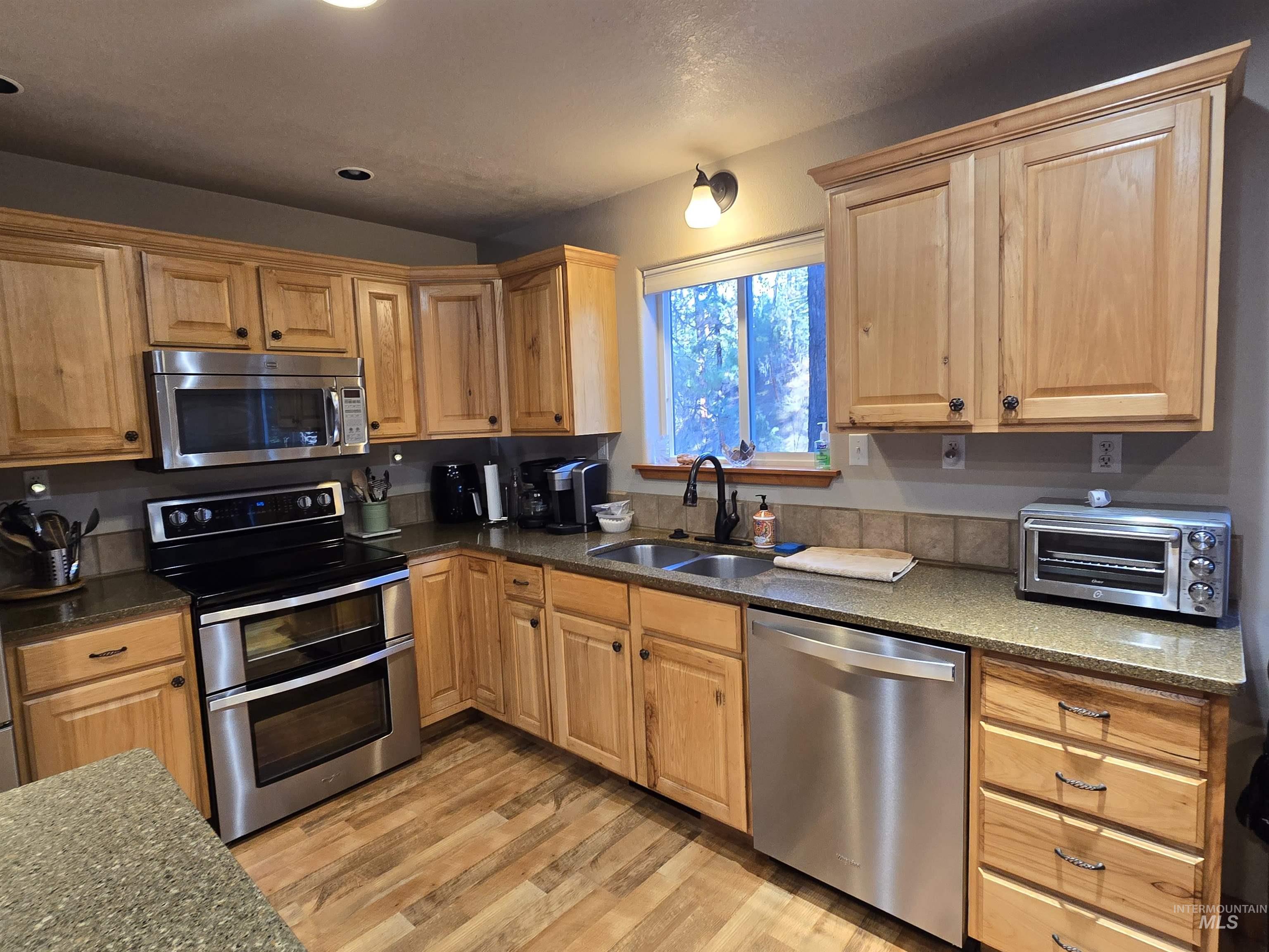 14 Forest Trail Road Garden Valley, ID 83622 - Photo 8 of 45 Kitchen with stainless steel appliances, light wood finished floors, and dark stone counters
