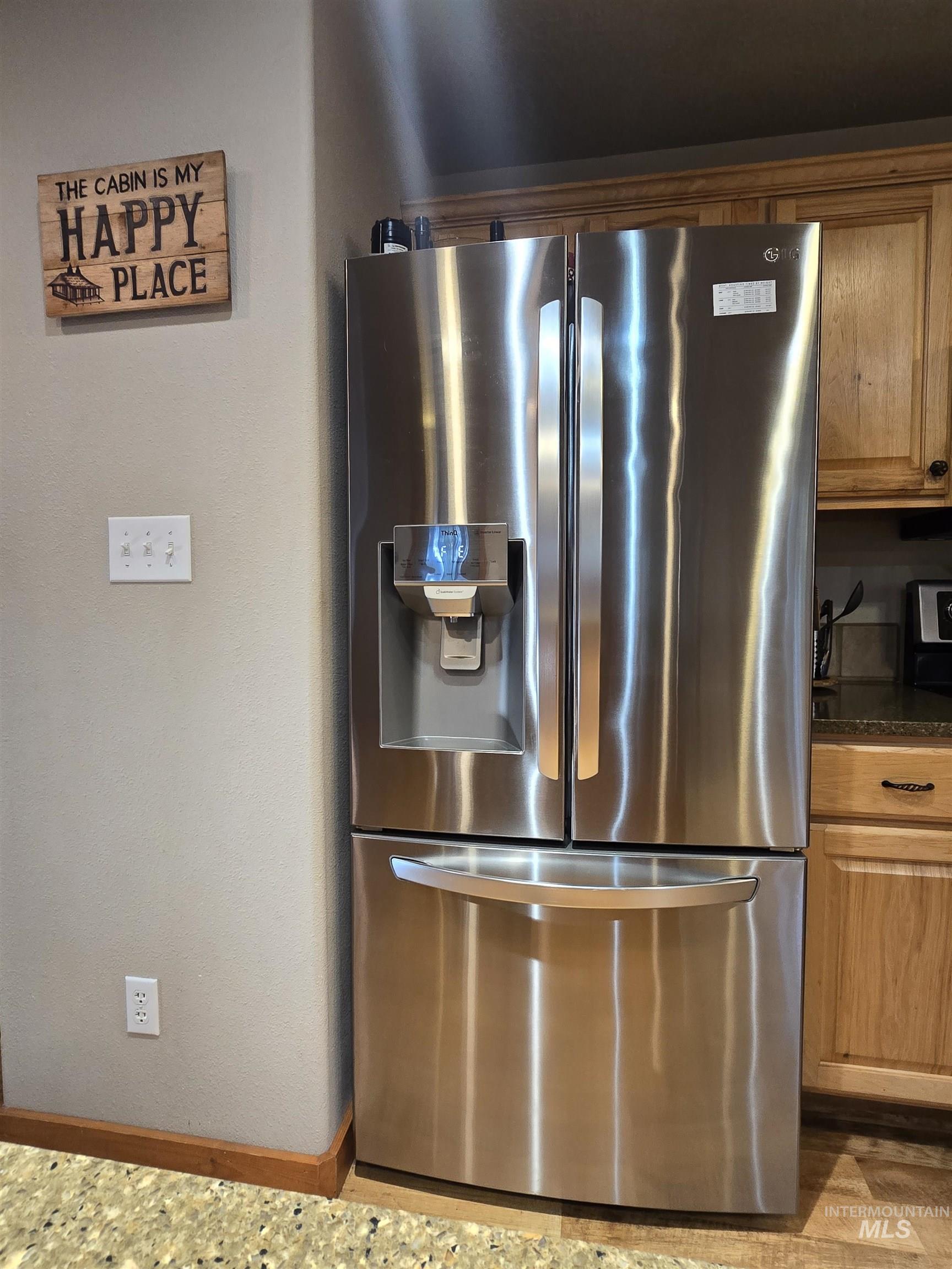 14 Forest Trail Road Garden Valley, ID 83622 - Photo 9 of 45 Kitchen view of stainless steel fridge with ice dispenser, dark stone countertops, and wood finish cabinets