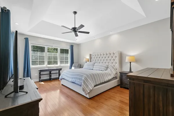 a bedroom with a large bed a chandelier and a window