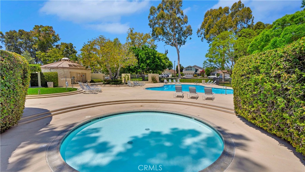 56 Wetstone, Unit 35 Irvine, CA 92604 - Photo 21 of 36 a view of a swimming pool with a yard and trees in the background