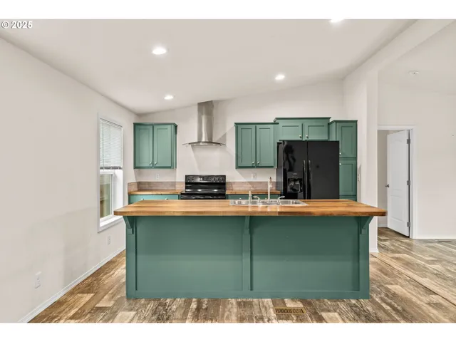 a kitchen with kitchen island a stove a refrigerator a sink dishwasher with wooden cabinets and wooden floor