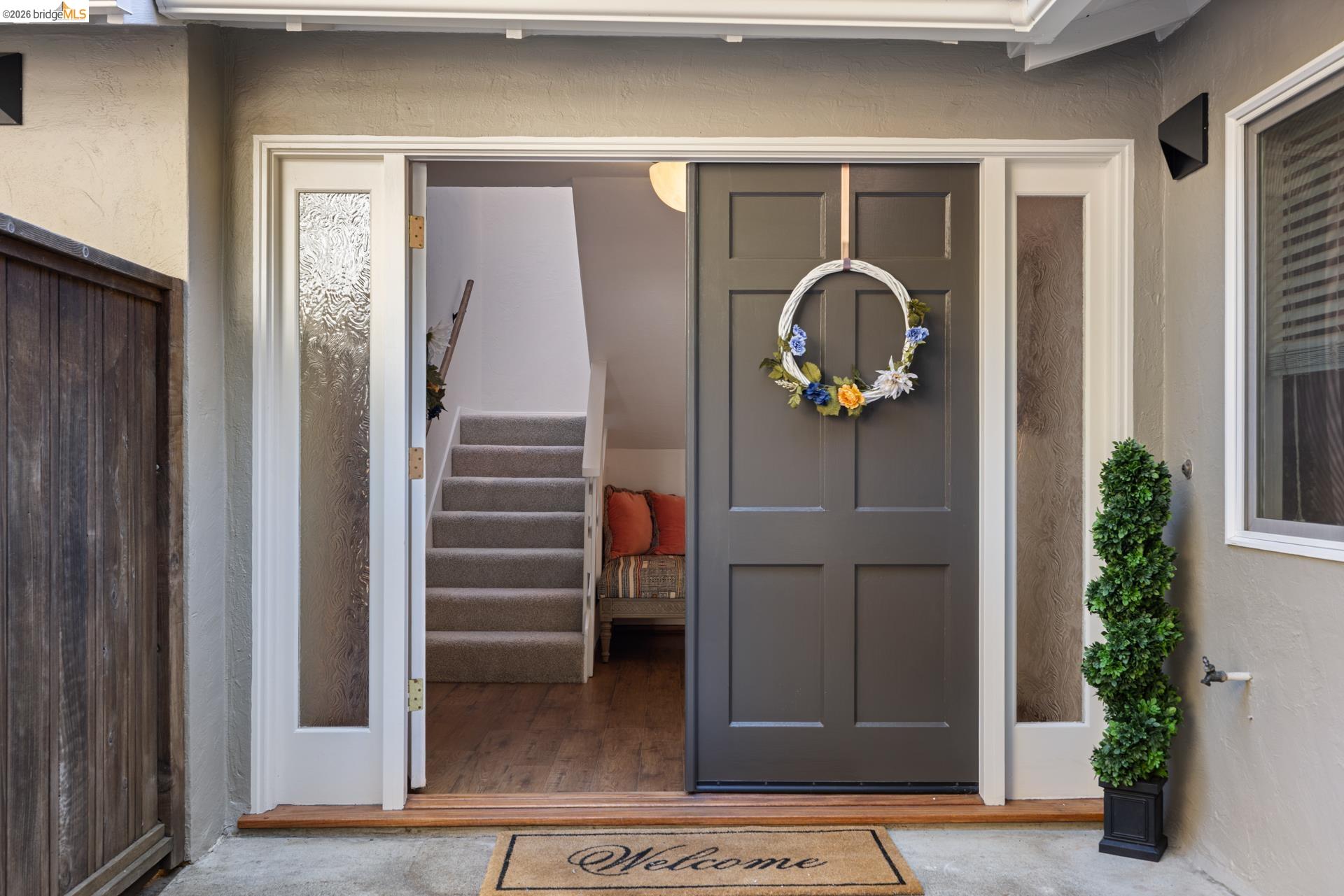 6660 Sobrante Road Oakland, CA 94611 - Photo 2 of 48 Paneled entry door with sidelights, wood-finish flooring, and a carpeted staircase