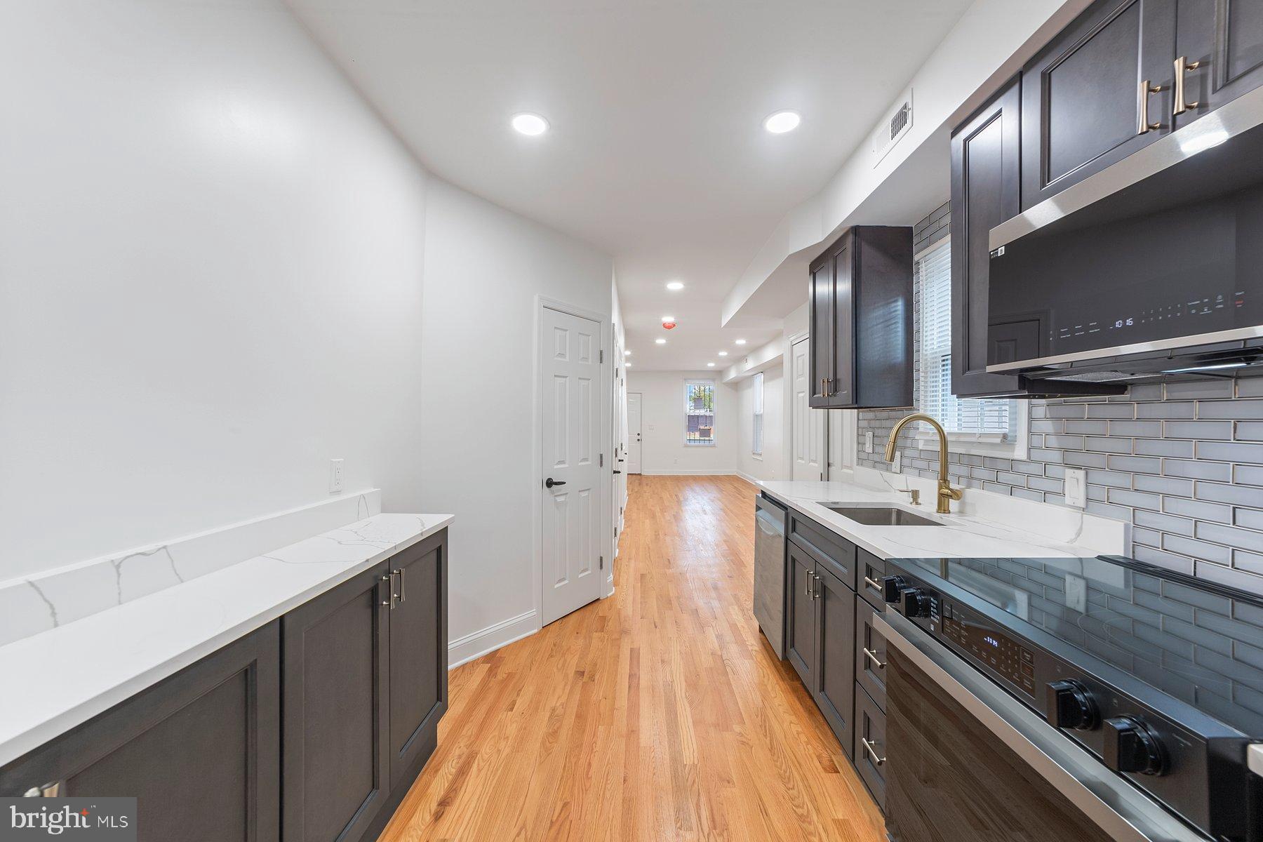 1325 W Street Southeast Washington, DC 20020 - Photo 5 of 26 a kitchen with stainless steel appliances granite countertop a sink a stove and a wooden floors