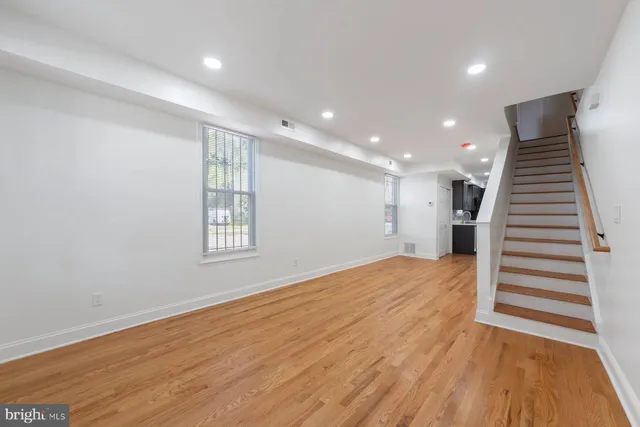 a view of an empty room with wooden floor and stairs