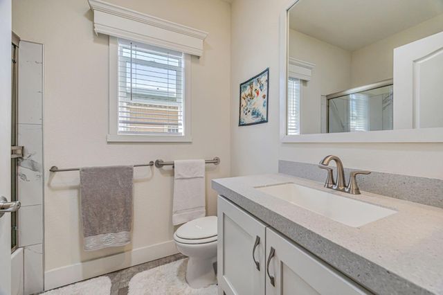 a bathroom with a granite countertop sink a toilet and a shower