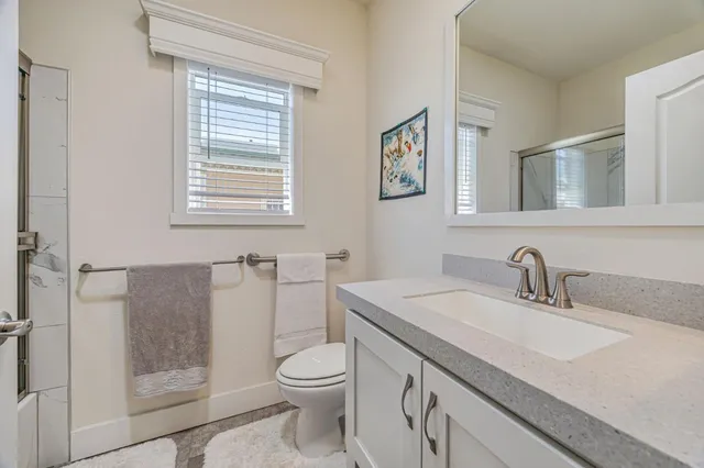 a bathroom with a granite countertop sink a toilet and a shower