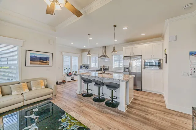 a living room with stainless steel appliances kitchen island granite countertop furniture and a wooden floor