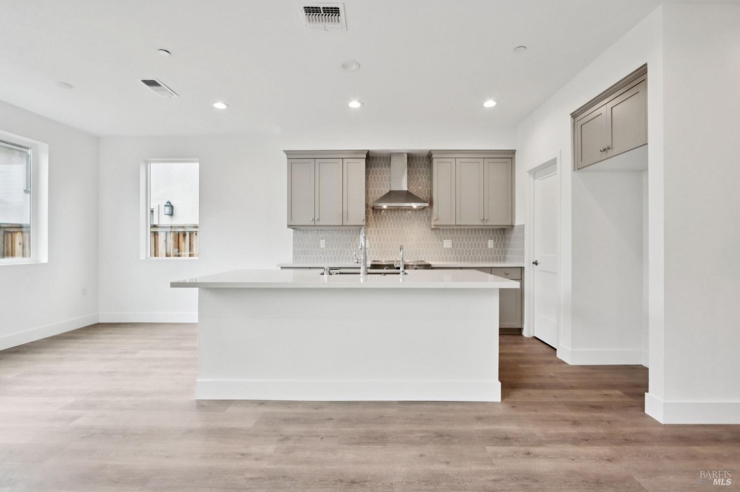 1556 Country Manor Drive Santa Rosa, CA 95403 - Photo 17 of 40 a large white kitchen with kitchen island a sink wooden floor and a refrigerator