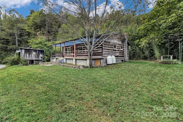 a backyard of a house with plants and tree with wooden fence