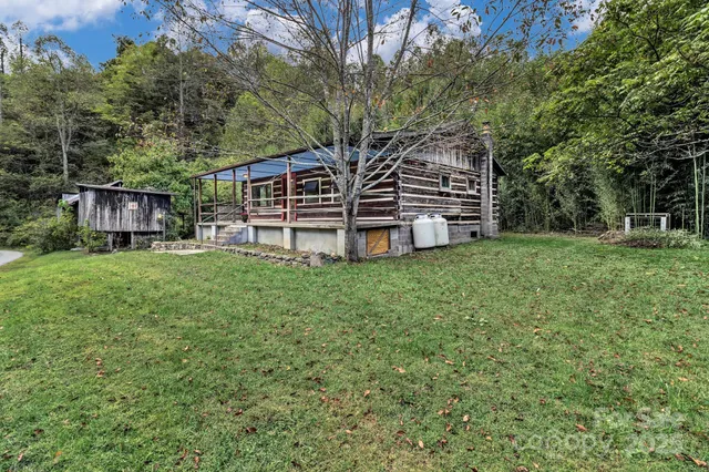 a backyard of a house with plants and tree with wooden fence