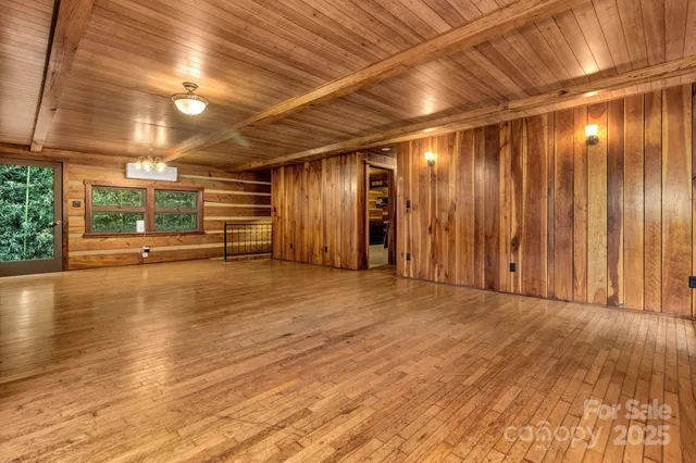 a view of a room with lots of wooden furniture and large windows